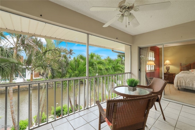 sunroom / solarium featuring ceiling fan and a water view