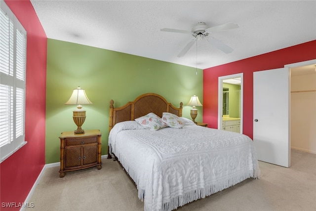 carpeted bedroom with ensuite bathroom, ceiling fan, and a textured ceiling