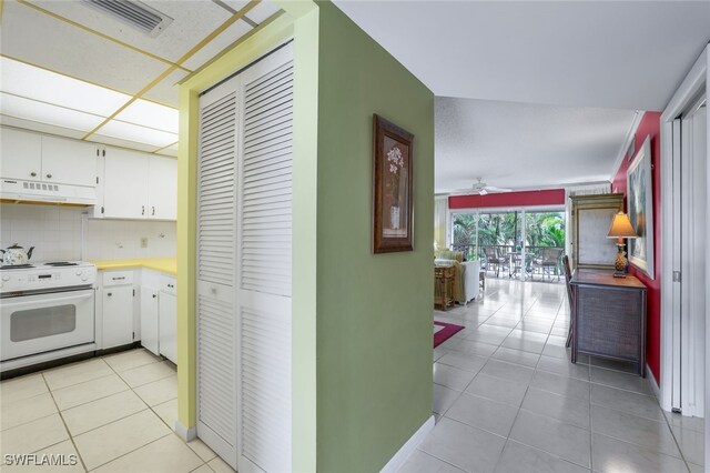 1200 Cherrystone Ct Unit B209, Naples, FL 34102 - kitchen featuring white electric range, under cabinet range hood, light tile patterned floors, and white cabinetry