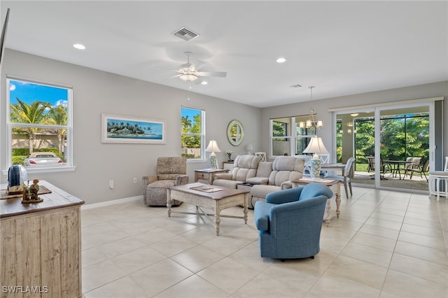 living room with ceiling fan with notable chandelier, a healthy amount of sunlight, and light tile patterned flooring