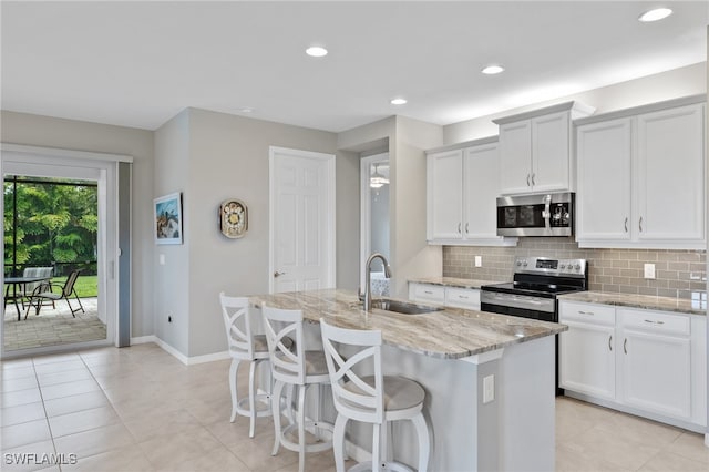 kitchen featuring stainless steel appliances, white cabinetry, a center island with sink, and sink