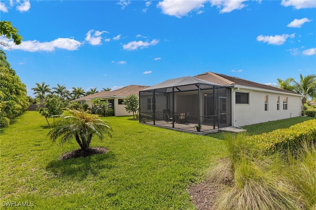 back of property featuring a lawn, glass enclosure, and a patio