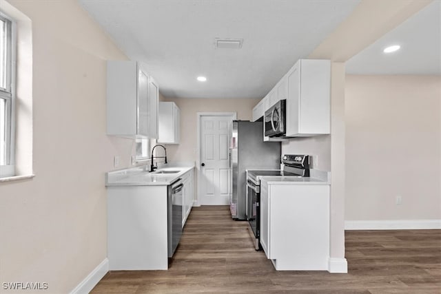 kitchen featuring appliances with stainless steel finishes, hardwood / wood-style flooring, white cabinetry, and sink