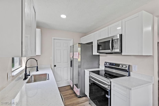 kitchen with white cabinets, light stone counters, sink, and appliances with stainless steel finishes