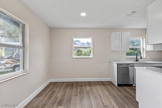 kitchen featuring white cabinetry, stainless steel dishwasher, plenty of natural light, and light hardwood / wood-style flooring