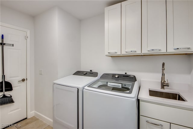 clothes washing area featuring cabinets, independent washer and dryer, light tile patterned flooring, and sink