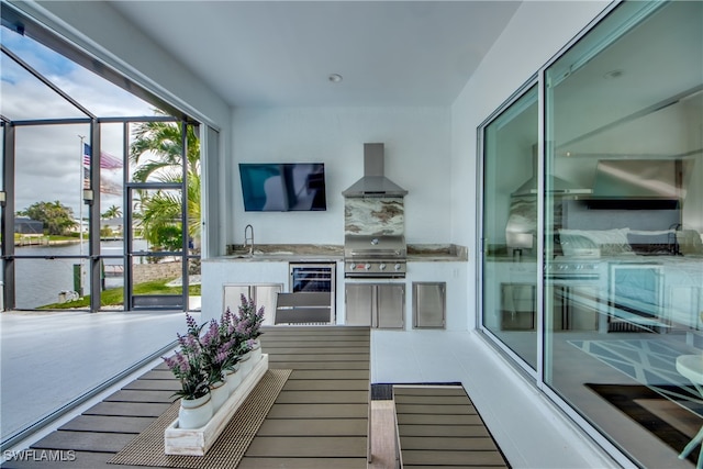 balcony with an outdoor kitchen, beverage cooler, sink, a patio, and a grill