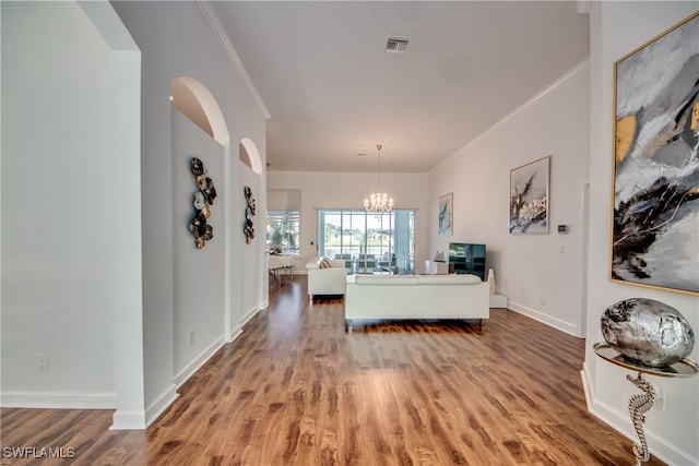 living room with hardwood / wood-style floors, an inviting chandelier, and ornamental molding