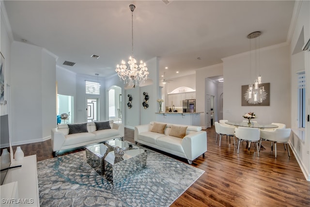 living room featuring dark hardwood / wood-style flooring, ornamental molding, and a notable chandelier