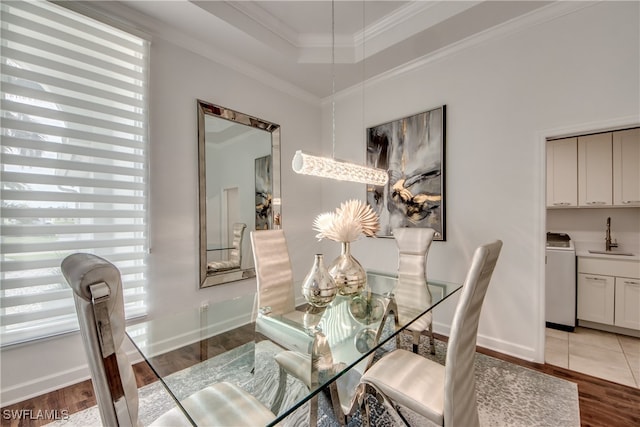 dining room with washer / dryer, ornamental molding, sink, and light hardwood / wood-style flooring