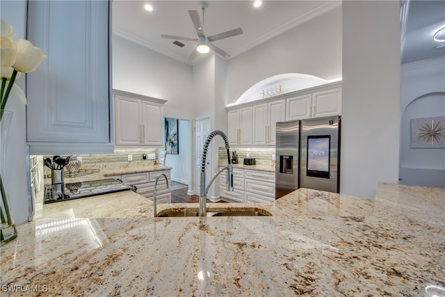 kitchen featuring light stone countertops, sink, stainless steel fridge, decorative backsplash, and hardwood / wood-style flooring