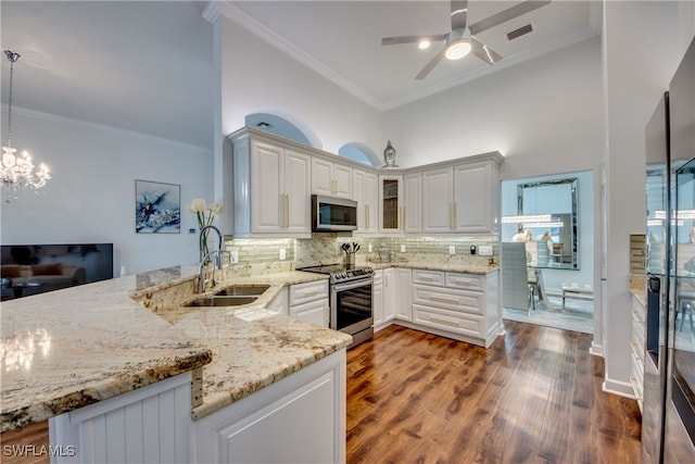 kitchen featuring white cabinetry, sink, kitchen peninsula, decorative light fixtures, and appliances with stainless steel finishes