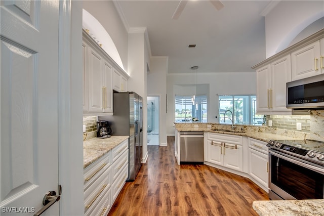 kitchen with appliances with stainless steel finishes, backsplash, sink, hardwood / wood-style flooring, and decorative light fixtures