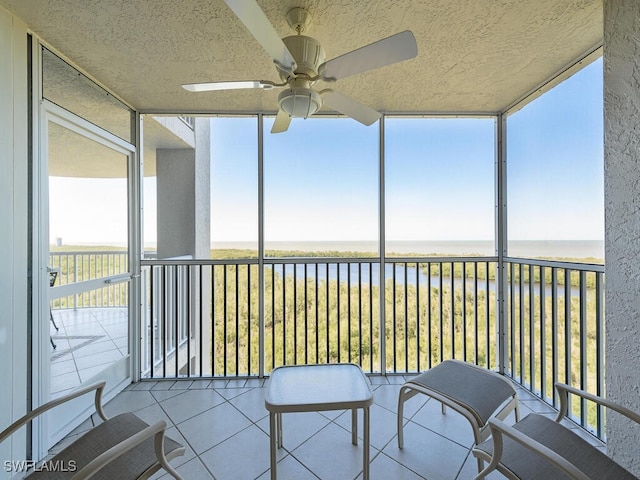 sunroom featuring a water view, a wealth of natural light, and ceiling fan