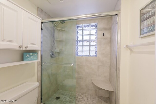 bathroom featuring toilet and a shower with shower door