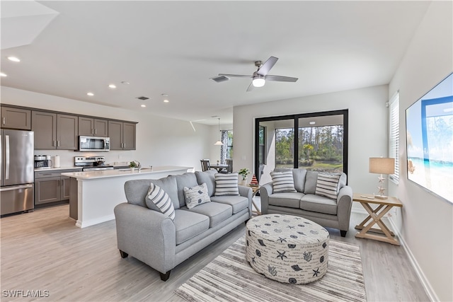 living room with ceiling fan and light hardwood / wood-style flooring