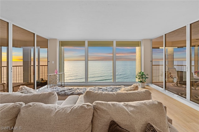 bedroom featuring access to exterior, a water view, and hardwood / wood-style flooring