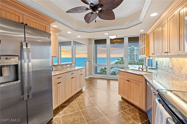 kitchen featuring sink, ornamental molding, light brown cabinetry, a tray ceiling, and stainless steel appliances