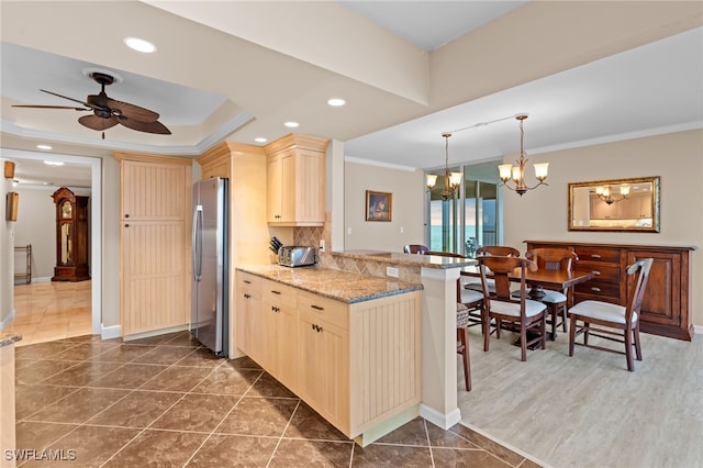 kitchen with kitchen peninsula, light brown cabinetry, ceiling fan with notable chandelier, and stainless steel refrigerator