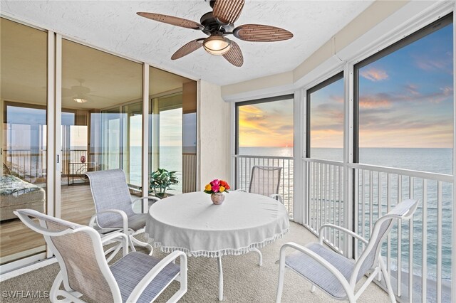 sunroom / solarium featuring a water view and ceiling fan