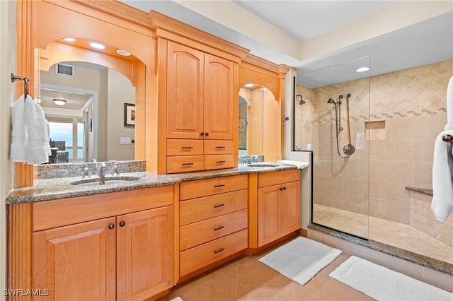 bathroom with tile patterned floors, a sink, visible vents, double vanity, and a walk in shower