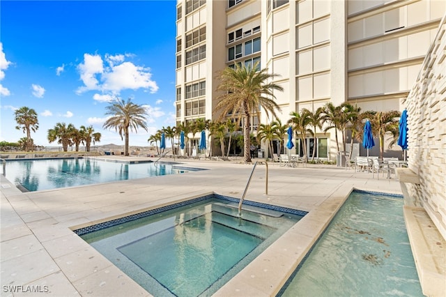 view of swimming pool featuring a patio and a hot tub