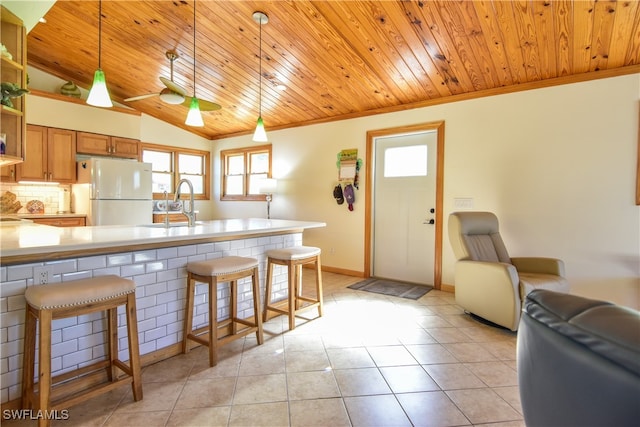 kitchen with a kitchen breakfast bar, decorative light fixtures, white fridge, lofted ceiling, and light tile patterned flooring