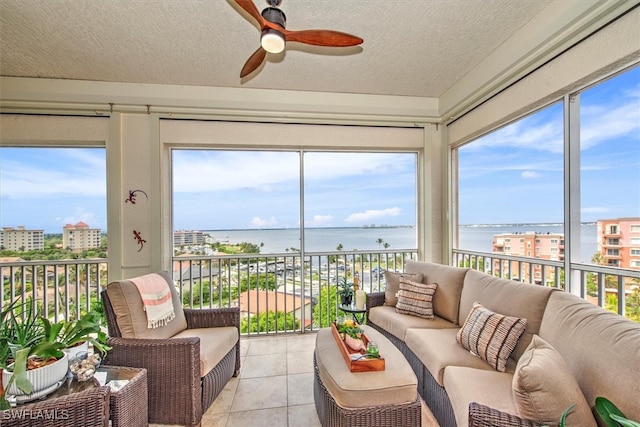 sunroom featuring ceiling fan and a water view