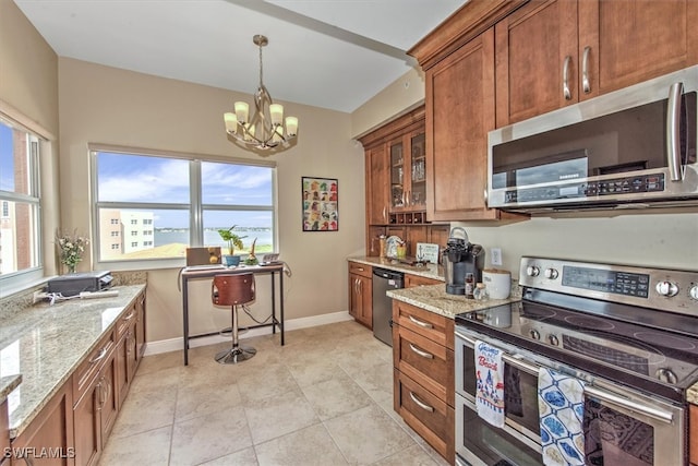 kitchen featuring a chandelier, a wealth of natural light, light stone countertops, and stainless steel appliances