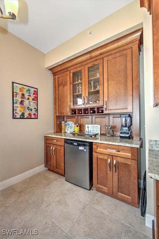 kitchen with dishwasher, light tile patterned flooring, and light stone countertops