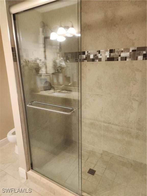 full bath featuring a stall shower, baseboards, and toilet