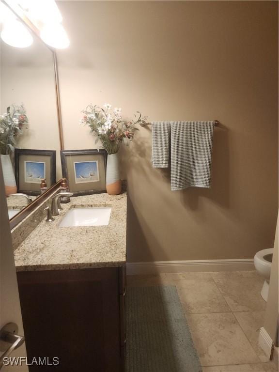 bathroom with toilet, tile patterned floors, baseboards, and vanity