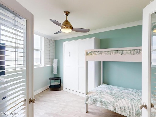 bedroom featuring ceiling fan, light hardwood / wood-style floors, crown molding, and multiple windows