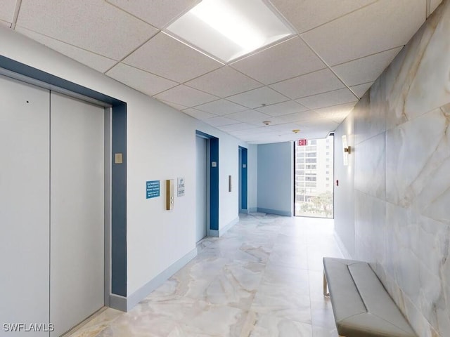 hallway with elevator and a drop ceiling