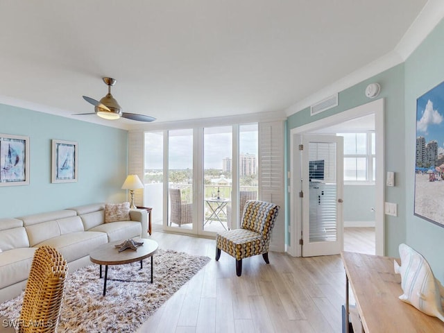 living room with ceiling fan, plenty of natural light, light hardwood / wood-style floors, and ornamental molding