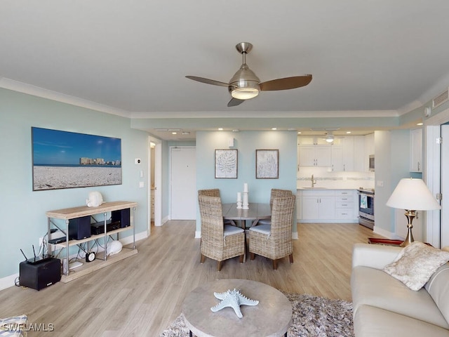 dining room with ceiling fan, sink, crown molding, and light hardwood / wood-style flooring