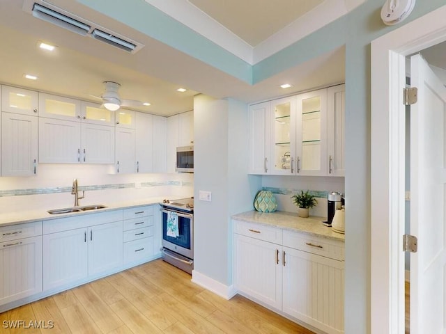 kitchen with white cabinetry, sink, light hardwood / wood-style floors, and appliances with stainless steel finishes