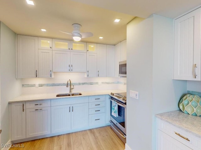 kitchen with white cabinets, sink, light hardwood / wood-style flooring, ceiling fan, and stainless steel appliances