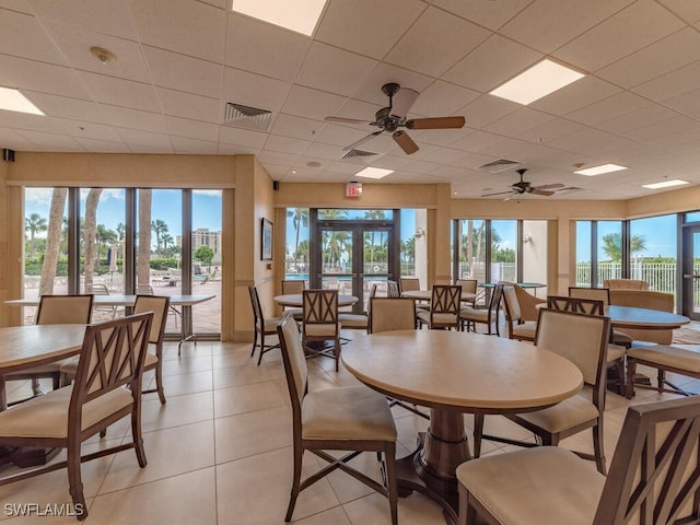 tiled dining space featuring ceiling fan, french doors, and a drop ceiling