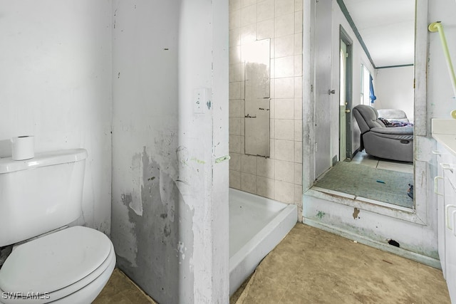 bathroom featuring tiled shower and toilet