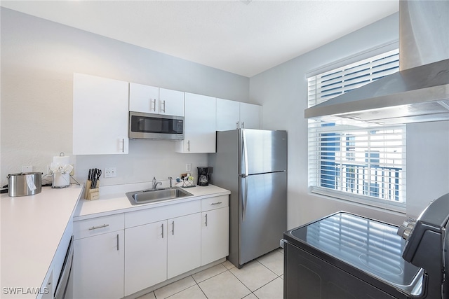 kitchen with wall chimney exhaust hood, stainless steel appliances, sink, light tile patterned floors, and white cabinets