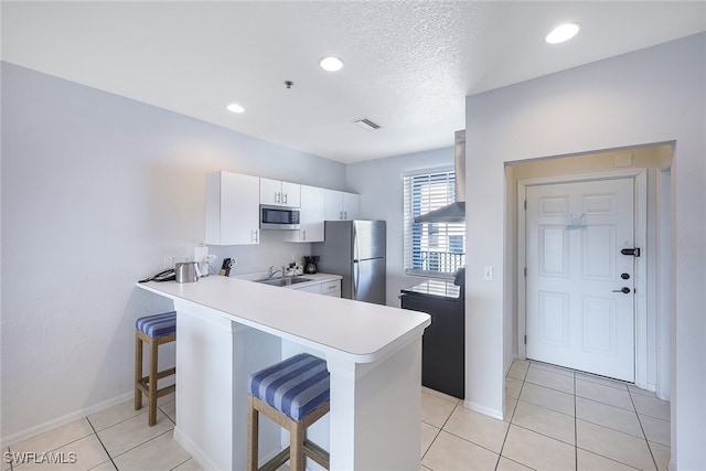 kitchen with white cabinets, a breakfast bar, kitchen peninsula, and appliances with stainless steel finishes