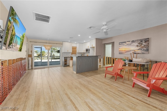 living room with light hardwood / wood-style floors and ceiling fan with notable chandelier