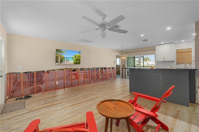 living room with light hardwood / wood-style floors, ceiling fan, and sink