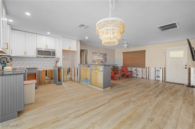 kitchen with a breakfast bar, light hardwood / wood-style floors, white cabinetry, and tasteful backsplash