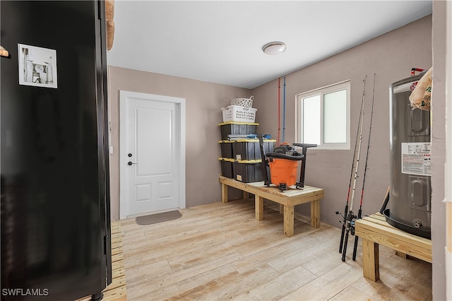 misc room featuring electric water heater and light hardwood / wood-style flooring