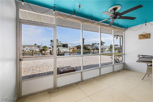 unfurnished sunroom featuring ceiling fan and a water view