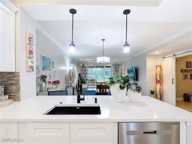 kitchen featuring a barn door, sink, white cabinets, and ornamental molding