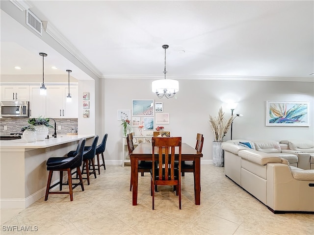 dining space with crown molding, sink, and a notable chandelier