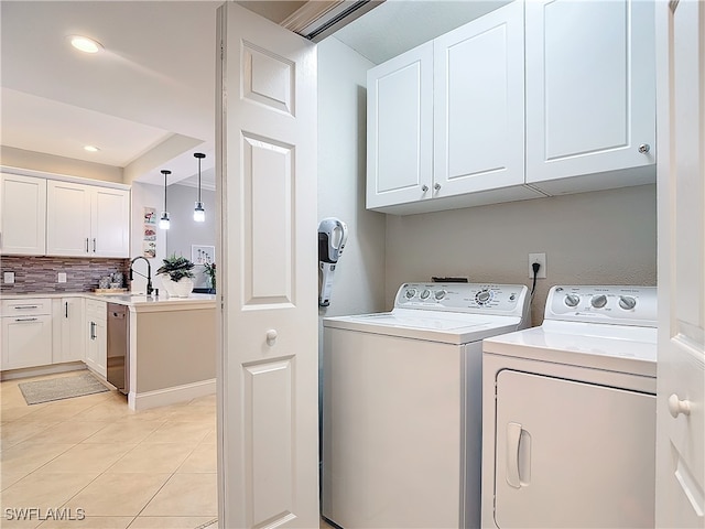 laundry area with cabinets, washing machine and dryer, light tile patterned floors, and sink